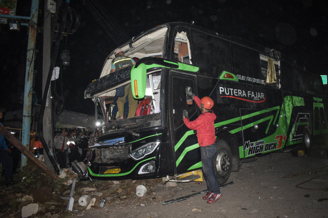 Petugas memeriksa bus yang rusak pasca kecelakaan yang menewaskan 11 orang, menurut polisi setempat, di Subang, Jawa Barat (11/5/2024). Foto: Timur Matahari / AFP