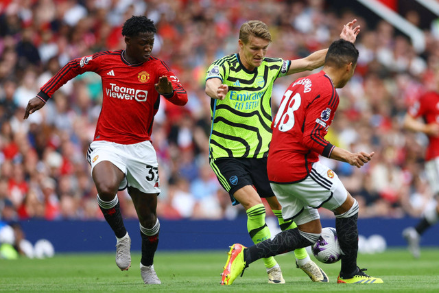 Pemain Manchester United Kobbie Mainoo dan Casemiro berebut bola dengan pemain Arsenal Martin Odegaard pada pertandingan lanjutan Liga Inggris di Old Trafford, Manchester, Inggris, Minggu (12/5/2024). Foto: Carl Recine/REUTERS