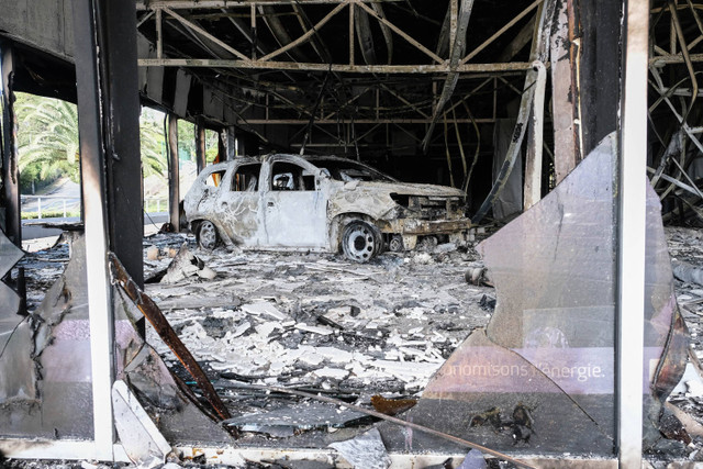 Mobil yang terbakar di toko dealer mobil di distrik PK4 di Noumea, Kaledonia Baru (14/5/2024). Foto: Theo Rouby / AFP