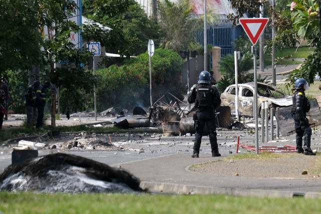 Petugas polisi Prancis menjaga pintu masuk distrik Vallee-du-Tir, saat kerusuhan terjadi di Noumea, Kaledonia Baru (14/5/2024). Foto: Theo Rouby/AFP