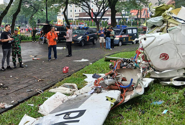 Sejumlah petugas berada di samping puing-puing pesawat yang jatuh di BSD Serpong, Tangerang Selatan, Banten, Minggu (18/5/2024). Foto: Rais Fauzan Azhar / ANTARA FOTO