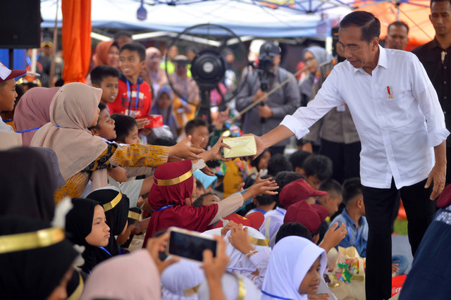 Presiden Jokowi (kanan) membagikan makanan kepada anak sekolah di posko pengungsian Nagari Batu Taba, Agam, Sumatera Barat, Selasa (21/5/2024). Foto: Iggoy el Fitra/Antara Foto