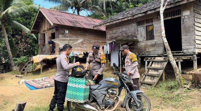 Kapolsek Nanga Mahap bersama Bhabinkamtibmas berkeliling desa membawa bantuan sembako menggunakan sepeda motor. Foto: Dok. Polsek Nanga Mahap