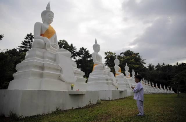 Seorang anak sedang berdoa di depan patung Buddha di Vihara Arama Kebun Kesadaran Kolongan, Tawaan, Minahasa Utara