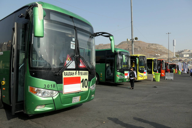 Petugas Penyelenggara Ibadah Haji (PPIH) Arab Saudi berjalan di depan deretan bus Shalawat di Terminal Syib Amir, Makkah, Arab Saudi, Kamis (23/5/2024). Foto: Sigid Kurniawan/Antara Foto