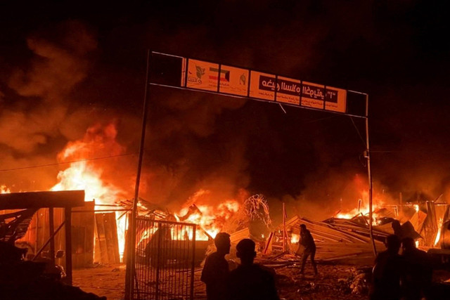 Api berkobar setelah serangan Israel di daerah yang diperuntukkan bagi pengungsi Palestina di tengah konflik yang sedang berlangsung antara Israel dan Hamas di Rafah di Jalur Gaza selatan (26/5/2024). Foto: REUTERS melalui REUTERS TV