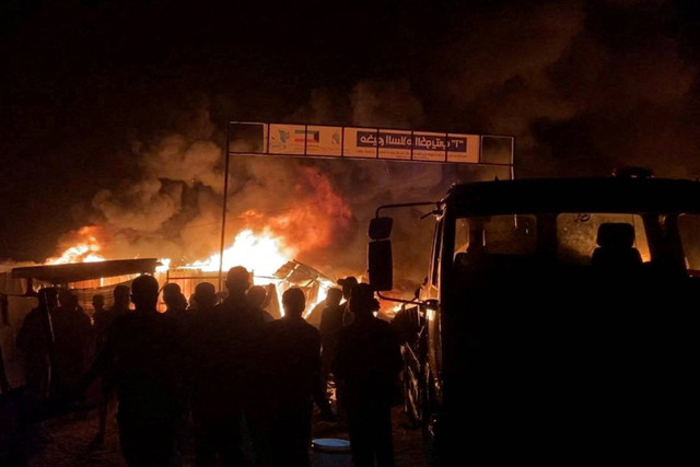 Api berkobar akibat serangan Israel di daerah yang diperuntukkan bagi pengungsi Palestina di tengah konflik yang sedang berlangsung antara Israel dan Hamas di Rafah di Jalur Gaza selatan (26/5/2024). Foto: REUTERS melalui REUTERS TV