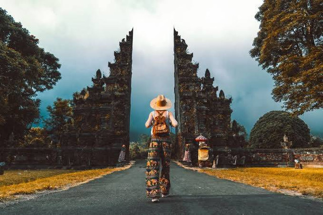 Foto Cover: Ilustrasi seorang wisatawan mancanegara sedang megunjungi salah satu situs di Bali. (Shutterstock/DavideAngelini)