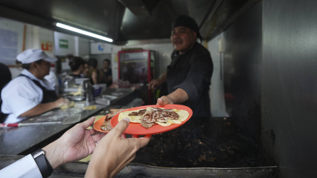 Seorang Koki berbintang Michelin Arturo Rivera Martinez memberikan pesanan taco kepada pelanggan di kedai taco Tacos El Califa de Leon, di Mexico City, Rabu, 15 Mei 2024.  Foto: AP/Fernando Llano