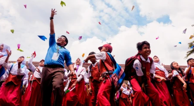 Tangerang, Indonesia, 2016: porait happy teacher and his students jump flying a paper plane after class celebrate exam is over (Foto : Shutterstock/masrob)