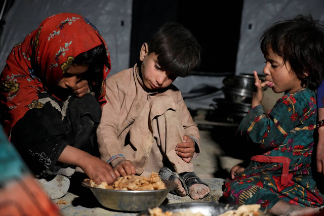 Anak-anak Afghanistan makan di tempat penampungan darurat setelah gempa bumi di distrik Gayan di provinsi Paktika, Afghanistan, Sabtu, 25 Juni 2022. Foto: Ebrahim Nooroozi/AP Photo