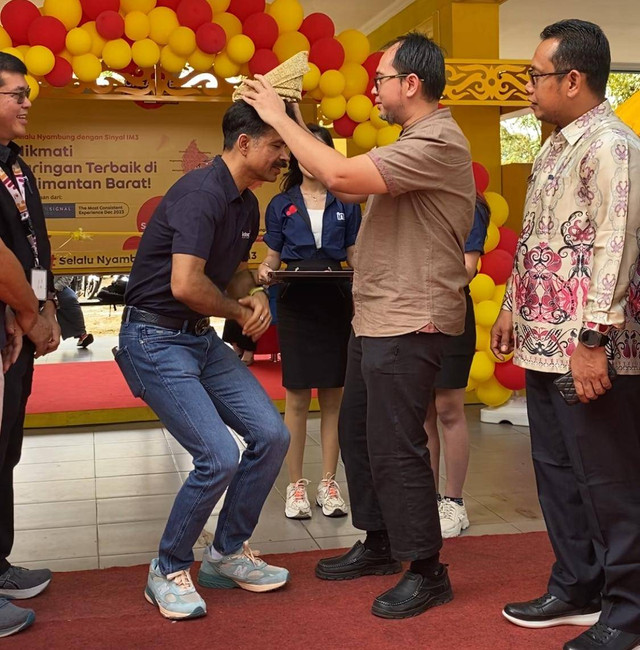 Wakil Rektor I IKIP PGRI Pontianak, Aunurahman saat mengenakan tanjak ke Director & Chief Commercial Officer Indosat Ooredoo Hutchison, Ritesh Kumar Singh. Foto: Yulia Ramadhiyanti/Hi!Pontianak