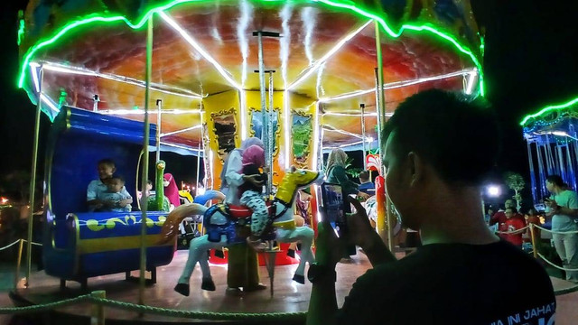 Seorang warga yang mengabadikan keluarganya di arena wisata permainan G-Walk yang menjadi tempat favorit masyarakat urban di Palembang, Minggu (2/6) Foto: ary piyanto/urban id