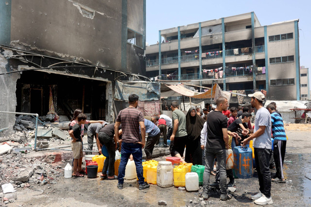 Warga Palestina mengisi air ke dalam jeriken di antara puing-puing bangunan yang hancur di kamp pengungsi Jabalia, di Jalur Gaza utara, Senin (3/6/2024). Foto: Omar Al Qatta / AFP