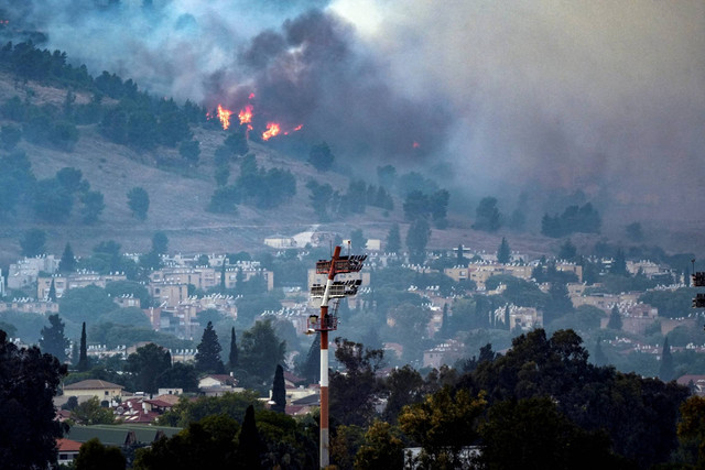 Asap dan api menutupi area tersebut setelah serangan roket dari Lebanon, di tengah permusuhan lintas batas yang sedang berlangsung antara Hizbullah dan pasukan Israel, dekat Kiryat Shmona, Israel, dekat perbatasannya dengan Lebanon, Senin (3/6/2024). Foto: REUTERS/Ayal Margolin ISRAEL OUT