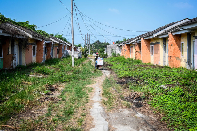 Pedagang melintas di dekat rumah yang kondisinya tidak terawat di perumahan subsidi Villa Kencana Cikarang, Kabupaten Bekasi, Jawa Barat, Rabu (5/6/2024). Foto: Rivan Awal Lingga/ANTARA FOTO