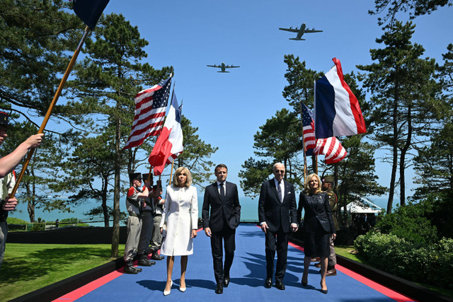 Presiden AS Joe Biden (kedua dari kanan) bersama Presiden Prancis Emmanuel Macron (kedua dari kiri) berjalan melewati para pembawa bendera selama AS upacara menandai peringatan 80 tahun pendaratan Sekutu "D-Day" Perang Dunia II di Prancis, (6/6). Foto: SAUL LOEB/AFP