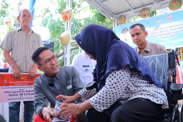 Pj Wali Kota Palembang, Ratu Dewa, saat menyerahkan bantuan kursi roda kepada penyandang disabilitas. (ist)