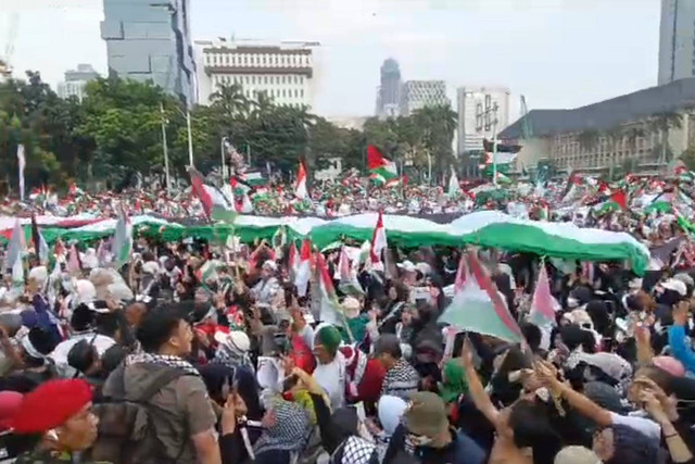 Massa aksi bela Palestina bentangkan bendera Palestina berukuran besar saat aksi bela Palestina di Kawasan Patung Kuda Arjuna Wiwaha, Jakarta Pusat, sore ini, Minggu (9/6/2024). Foto: Zamachsyari/kumparan