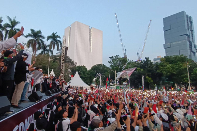 Massa aksi bela Palestina menyalakan flashlight dan mengangkat kartu merah saat aksi bela Palestina di Kawasan Patung Kuda Arjuna Wiwaha, Jakarta Pusat, sore ini, Minggu (9/6/2024). Foto: Zamachsyari/kumparan