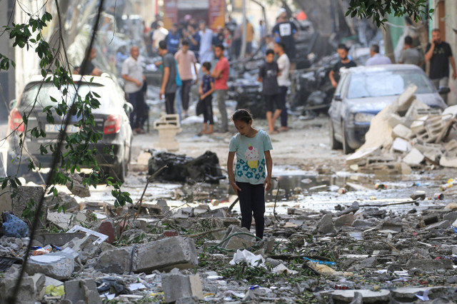 Seorang anak Palestina berjalan di antara puing-puing bangunan yang hancur usai serangan kamp pengungsi Nuseirat di Jalur Gaza tengah, Minggu (9/6/2024). Foto: Eyad BABA / AFP