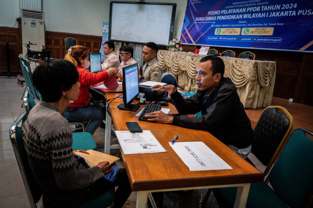 Petugas membantu orang tua murid dan calon peserta didik baru melakukan pengecekan status pendaftaran Penerimaan Peserta Didik Baru (PPDB) di Posko Pelayanan PPDB, Jakarta, Senin (10/6/2024). Foto: Bayu Pratama S/ANTARA FOTO