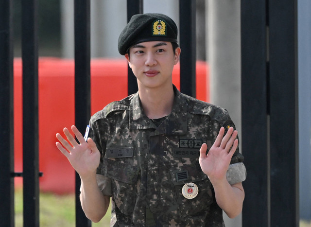 Personil BTS, Jin melambaikan tangan usai menyelesaikan wajib militer di luar pangkalan militer Yeoncheon, Korea Selatan, Rabu (12/6/2024).  Foto: JUNG YEON-JE / AFP