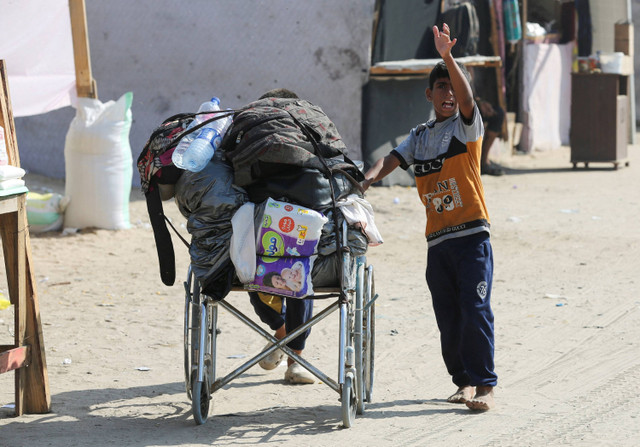 Seorang anak mendorong kursi roda membawa barang-barang ketika warga Palestina meninggalkan Rafah akibat operasi militer Israel di Rafah, Jalu Gaza, Kamis (13/6/2024). Foto: Hatem Khaled/REUTERS