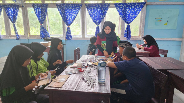 Seperti terlihat, adik-adik sangat antusias untuk membuat, merangkai dan menempelkan satu persatu sampul buku yang telah mereka gulung kecil-kecil selanjutnya dirangkai menjadi bingkai foto yang cantik dan menarik. (Foto : Simon Tampubolon/Yayasan Palung).