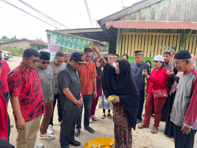 Ketua Komisi V DPR RI, Lasarus, disambut ritual adat Melayu Sintang saat tiba untuk memberikan bantuan sapi kurban di Menyumbung Tengah. Foto: Yusrizal/Hi!Pontianak