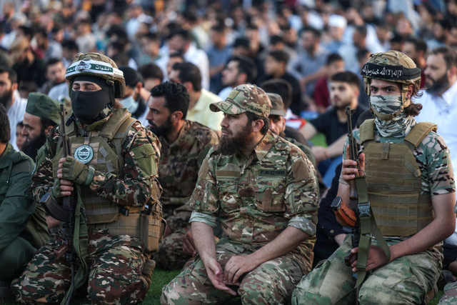 Pejuang militer yang berafiliasi dengan mantan afiliasi Al-Qaeda Hayat Tahrir al-Sham (HTS) melaksanakan Salat Idul Adha 1445 H di stadion terbuka, Kota Idlib, Suriah, Minggu (16/6/2024). Foto: Ted ALJIBE / AFP