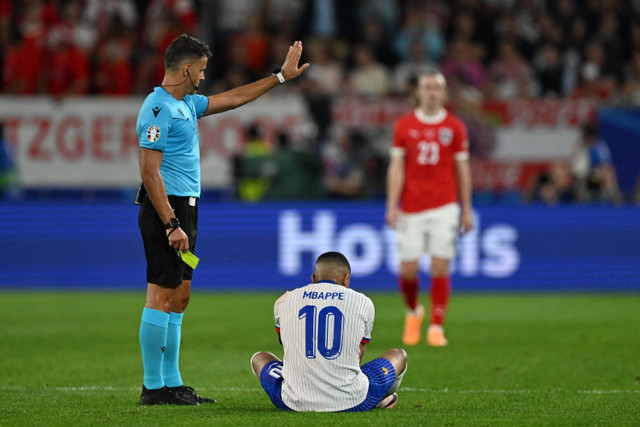 Wasit Jesus Gil Manzano bersiap untuk memberikan kartu kuning kepada pemain Timnas Prancis Kylian Mbappe saat melawan Timnas Austria pada pertandingan Grup D Piala Eropa 2024 di Duesseldorf Arena, Duesseldorf, Jerman, Senin (17/6/2024). Foto: PATRICIA DE MELO MOREIRA / AFP