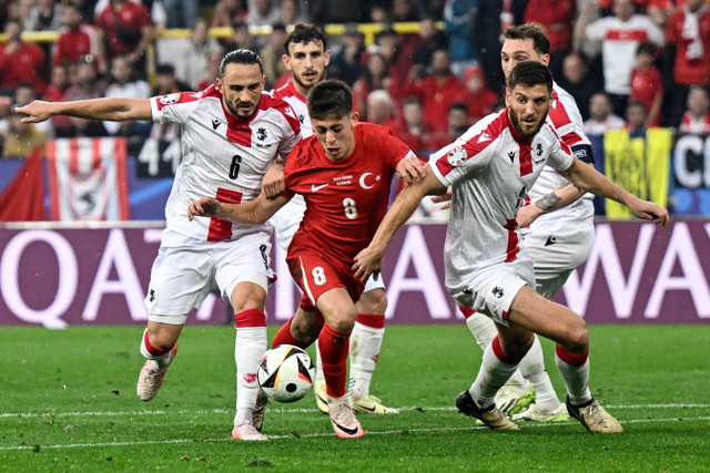 Pemain Timnas Turki Arda Guler berebut bola dengan pemain Timnas Georgia Giorgi Kochorashvili pada pertandingan Grup F Piala Eropa 2024 di Signal Iduna Park, Dortmund, Jerman, Selasa (18/6/2024). Foto: INA FASSBENDER / AFP