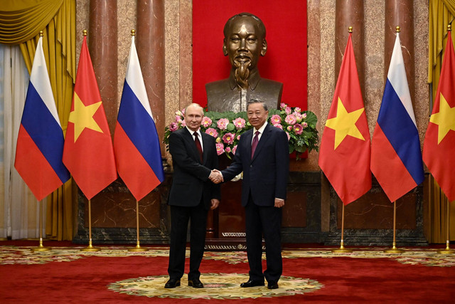 Presiden Rusia Vladimir Putin (kiri) dan Presiden Vietnam To Lam (kanan) bersalaman di Istana Kepresidenan di Hanoi, Vietnam, Kamis (20/6/2024). Foto: Nhac Nguyen/POOL/AFP