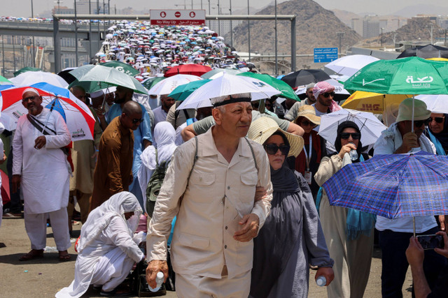 Jamaah haji berjalan dengan payung pada hari ketiga ritual rajam setan, di tengah cuaca yang sangat panas, selama ibadah haji tahunan, di Mina, Arab Saudi, 18 Juni 2024. Foto: REUTERS/Saleh Salem