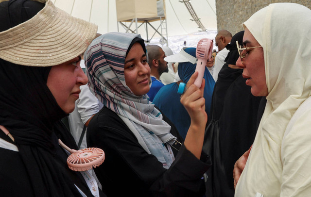 Seorang wanita mengipasi wajah seorang jamaah haji untuk menenangkan diri saat mereka menjalani ibadah, di tengah cuaca yang sangat panas, selama ibadah haji tahunan, di Mina, Arab Saudi, 18 Juni 2024.  Foto: REUTERS/Saleh Salem