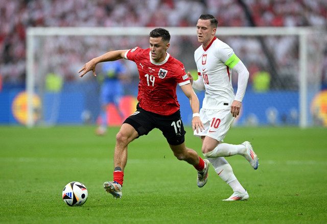 Duel Christoph Baumgartner & Piotr Zielinski saat Polandia vs Austria dalam laga kedua Grup D Piala Eropa 2024 yang digelar di Olympiastadion Berlin, Jerman, Jumat (21/6) malam WIB. Foto: REUTERS/Annegret Hilse