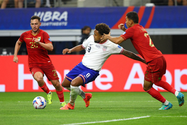 Pemain Amerika Serikat Weston McKennie berebut bola dengan pemain Bolivia Fernando Saucedo dan Jesus Sagredo pada pertandingan grup C turnamen Copa America 2024 antara Amerika Serikat dan Bolivia di Stadion AT&T di Arlington, Texas, Senin (24/6/2024) Foto: Aric Becker/AFP