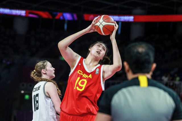 Pemain bola basket China setinggi 2,20 m Zhang Ziyu menembak melewati pemain Selandia Baru, Elise Jay saat pertandingan Piala Asia Putri U-18 FIBA 2024 antara China dan Selandia Baru di Shenzhen, provinsi Guangdong, China selatan, Selasa (25/6/2024). Foto: AFP