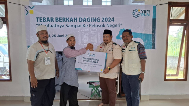 Ketua YBM PLN UID Kalbar Mukhlis Zarkasih (kanan) secara simbolis menyerahkan bantuan Tebar Berkah Daging Kepada Dai Pedalaman Ustaz Engkos Kosasih (kiri) di Masjid Al Mumawar Syeban Desa Jagoi, Kabupaten Bengkayang. Foto: Dok. PLN Kalbar