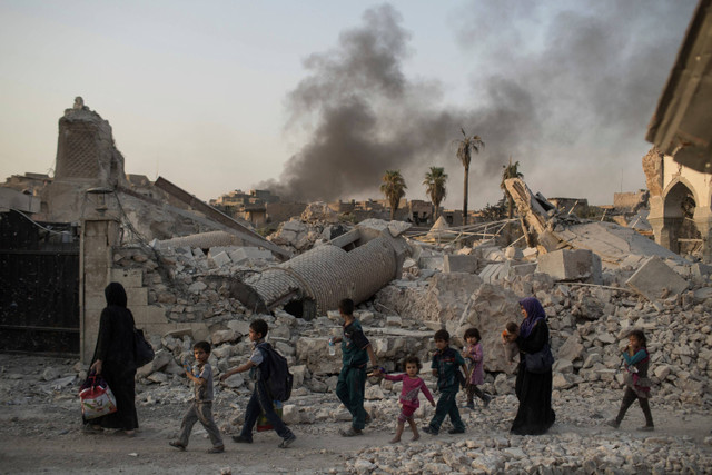 Warga berjalan di dekat masjid al-Nuri yang rusak berat saat pasukan Irak melanjutkan serangan mereka melawan militan ISIS di Kota Tua Mosul, Irak, pada 4 Juli 2017. Foto: Felipe Dana/ AP PHOTO