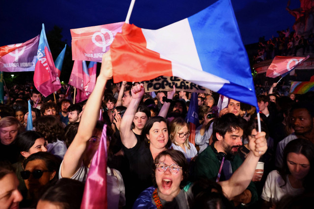 Para pengunjuk rasa mengibarkan bendera Prancis dan bendera "Persatuan Populer" untuk mendukung "Nouveau Front Populaire" (Front Populer Baru - NFP) di Paris, Prancis, Minggu (30/6/2024). Foto: Fabrizio Bensch/ REUTERS