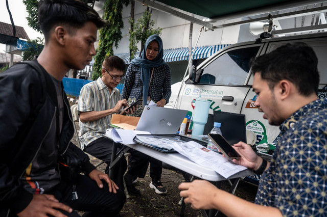 Petugas BPJS Kesehatan membantu pemohon Surat Izin Mengemudi memeriksa status aktif kepesertaan BPJS Kesehatan saat melakukan perpanjangan SIM di Satuan Penyelenggara Administrasi SIM Polda Metro Jaya, Daan Mogot, Selasa (2/7/2024). Foto: Aprilio Akbar/ANTARA FOTO