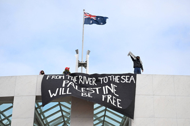 Pengunjuk rasa pro-Palestina menggantung spanduk di puncak Gedung Parlemen di Canberra, Australia, Kamis (4/7/2024). Foto: AAP/Lukas Coch/via REUTERS