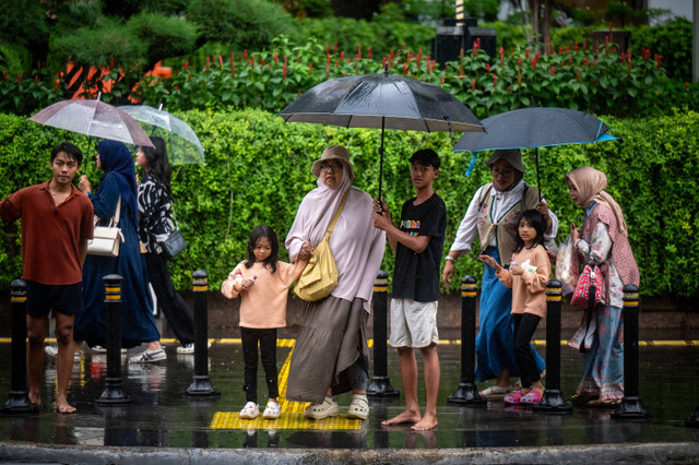 Sejumlah warga menggunakan payung saat turun hujan di kawasan Bundaran HI, Jakarta, Kamis (4/7/2024). Foto: Erlangga Bregas Prakoso/ANTARA FOTO