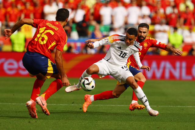 Pemain Timnas Jerman Jamal Musala berebut bola dengan pemain Timnas Spanyol Dani Carvajal pada pertandingan perempat final Piala Eropa 2024 di Stuttgart Arena, Stuttgart, Jerman, Jumat (5/7/2024). Foto: Kai Pfaffenbach/REUTERS