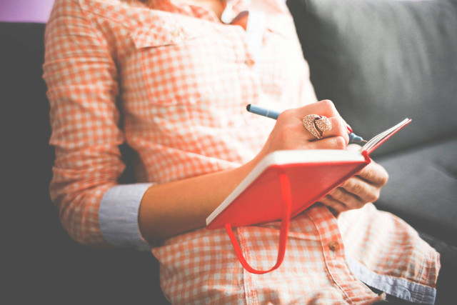 https://www.pexels.com/id-id/foto/orang-yang-menulis-di-buku-catatan-merah-261735/