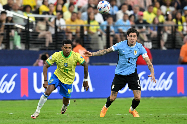 Pemain Timnas Brasil Rodrygo berebut bola dengan pemain Timnas Uruguay Jose Maria Gimenez pada pertandingan perempat final Copa America 2024 di Stadion Allegiant, Las Vegas, Nevada, Amerika Serikat, Sabtu (6/7/2024). Foto: Robyn Beck / AFP