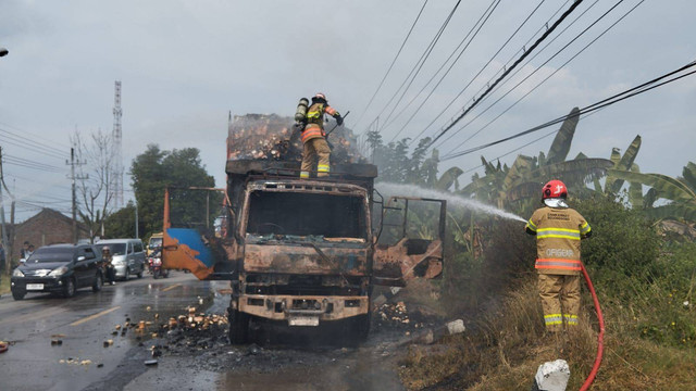 Petugas saat berusaha memadamkan api kebakaran truk bermuatan mie gelas instan di Jalan Raya Bojonegoro-Cepu, turut Desa Ngulanan, Kecamatan Dander, Kabupaten Bojonegoro, Jawa Timur. Rabu (10/07/2024). (Aset: Istimewa)