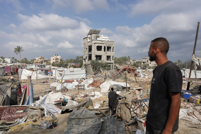 Seorang pria Palestina melihat tenda-tenda yang rusak di lokasi pengeboman Israel sehari sebelumnya di kamp pengungsian al-Mawasi di kota Khan Yunis di Jalur Gaza selatan, Minggu (14/7/2024). Foto: Bashar Taleb/AFP